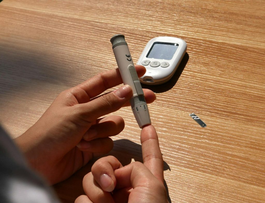 a person holding a blood sugar meter on a table